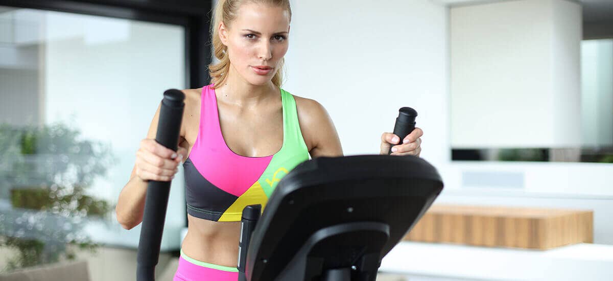 Frau trainiert mit Crosstrainer ihre Ausdauer